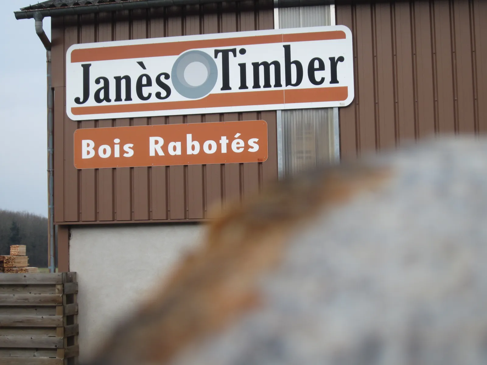Enseigne « Janès Timber – Bois rabotés » sur le bâtiment de l'entreprise